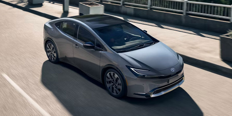 The Toyota cruising along a road, representing the evolution of hybrid vehicles in the 2026 vs 2025 comparison.