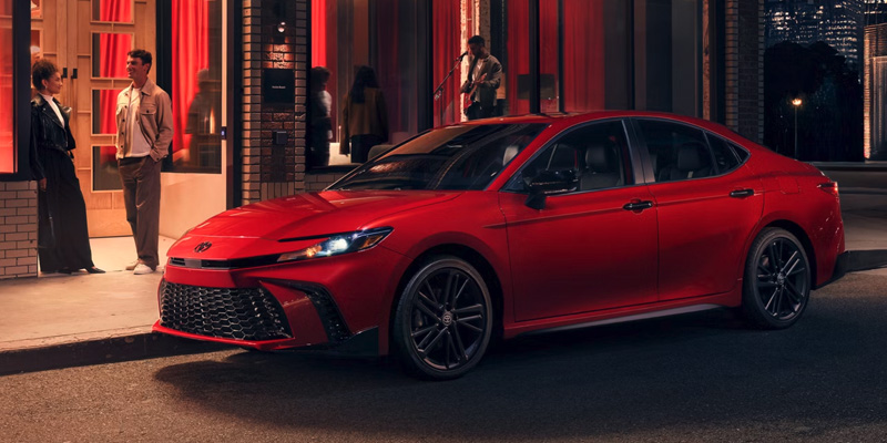 Toyota Camry parked in front of a building, illuminated by streetlights at night.